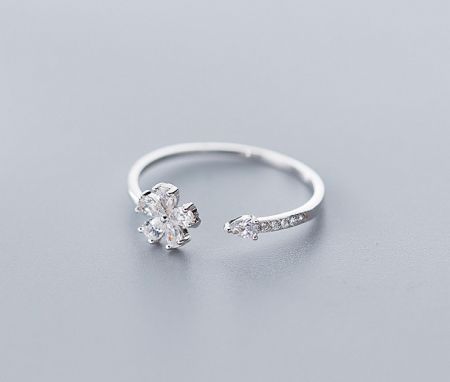 Detailed shot of the silver flower ring with its unique open band design and clear gemstone accents.