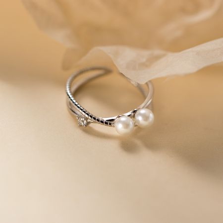 Detailed view of a 925 silver adjustable ring with textured band, two pearls, and a central CZ stone.
