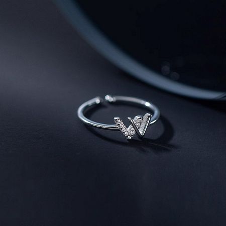 A close-up of the silver W initial ring on a neutral background, highlighting the zircon details.