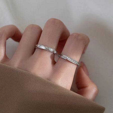 A hand modeling the sterling silver couple rings to showcase their elegant fit.