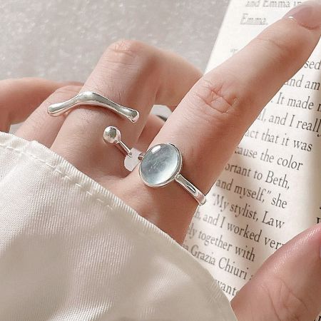 Model wearing two sterling silver rings from the set, one with an oval stone and one with a curved design.