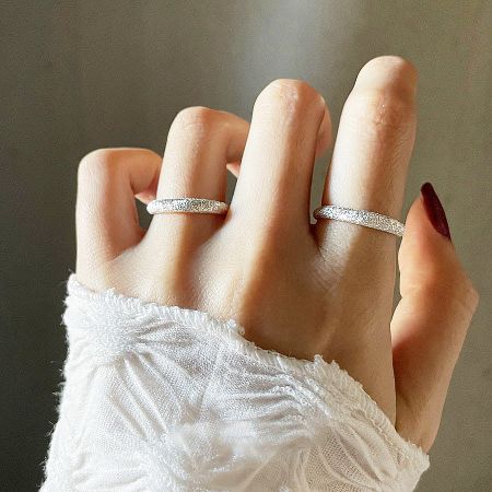 A model's hand wearing two sterling silver frosted open rings, showcasing their elegant fit.