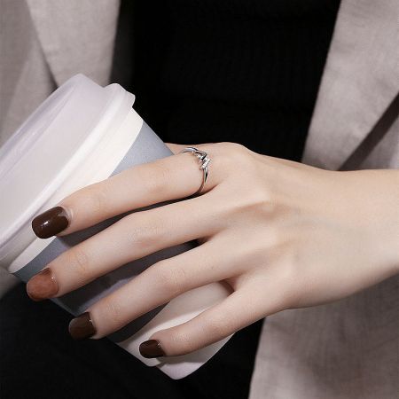 A lifestyle shot of the sterling silver W initial ring worn on a hand holding a coffee cup.