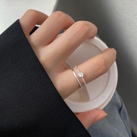 925 Sterling Silver Round Zircon Adjustable Rings - Set of 5 - A woman's hand wearing the 925 Sterling Silver Round Zircon Adjustable Rings, showcasing their elegant double-layer design while holding a cup of coffee.