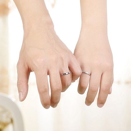 Woman's hands modeling the sterling silver couples rings.