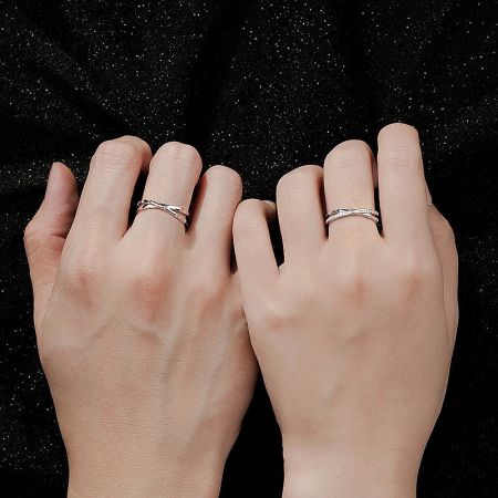 Close-up of the silver bamboo cross design rings worn on a model's hands.