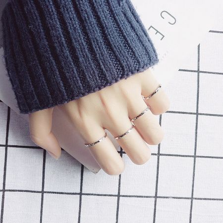 A set of five silver line stack rings showcased on a mannequin's hand.