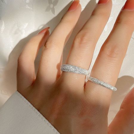 Close-up of the sparkling frosted texture on the 925 sterling silver rings worn on a finger.