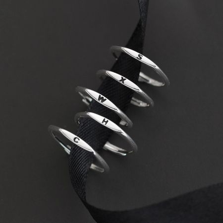 Close-up of five sterling silver alphabet rings with letters C, H, W, X, and S.