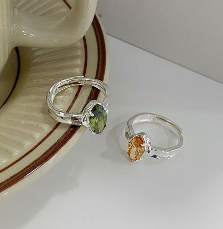 925 Sterling Silver Peridot, Champ Ring - A pair of 925 sterling silver rings, one with a vibrant green peridot gemstone and the other with a warm champagne-colored gemstone, showcasing the adjustable band design.