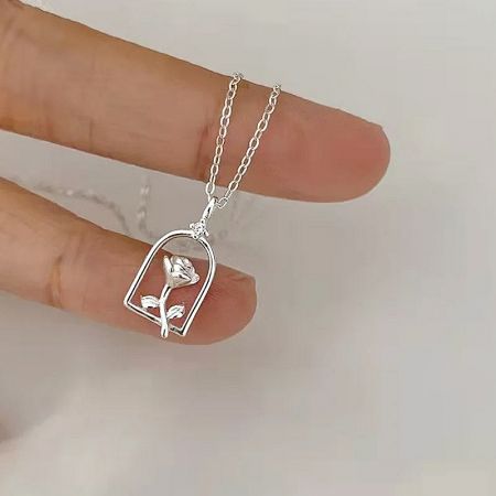 Close-up of the silver necklace pendant with an intricate rose in a glass dome.