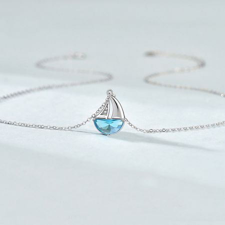 Detailed view of the sailboat pendant with its intricate light blue CZ gemstone.
