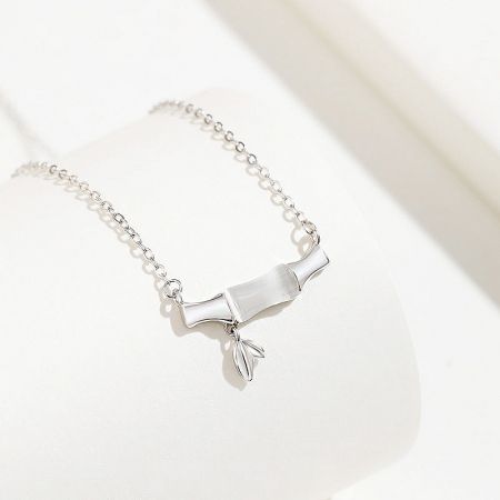 Detailed view of a sterling silver necklace with a scroll-shaped charm and delicate leaf pendant.