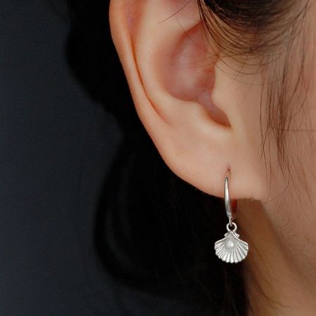 Model wearing the silver 925 sterling silver ocean pearl shell huggie hoop earring.