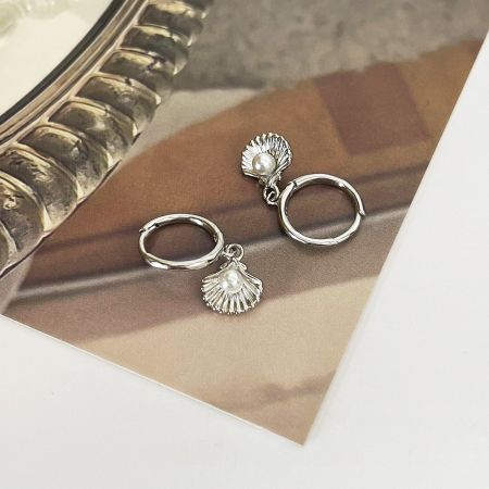 Close-up of the silver variant of the ocean pearl shell huggie hoop earring, showing intricate shell details.