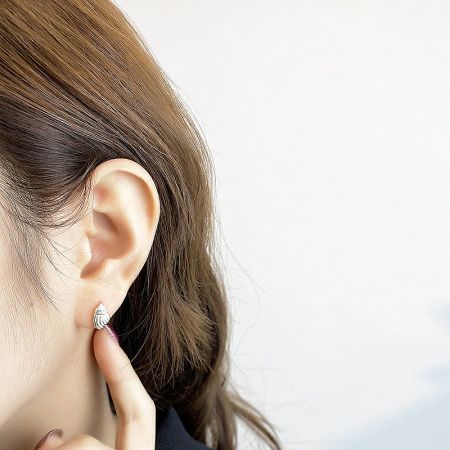 Close-up view of the silver seashell earring on a model's ear, emphasizing its elegant design.
