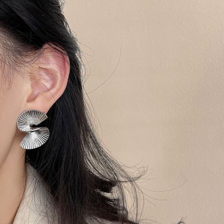 Close-up of the silver version of the geometric fan-shaped earring on a model.