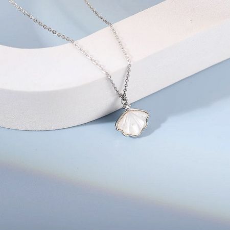 Professionally styled product shot of the silver sea shell necklace on a display stand.