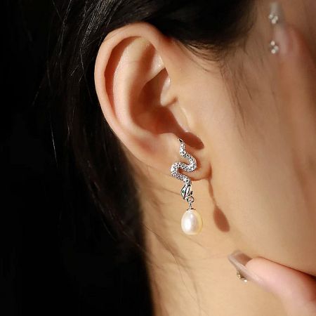 S925 Sterling Silver Gothic Punk Green-Eye Snake Pearl Drop Earrings - A pair of S925 sterling silver gothic punk earrings featuring a detailed green-eyed snake design with a dangling pearl drop, set against a white background.