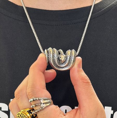 A person holding the detailed men's snake pendant, showcasing its size and craftsmanship.