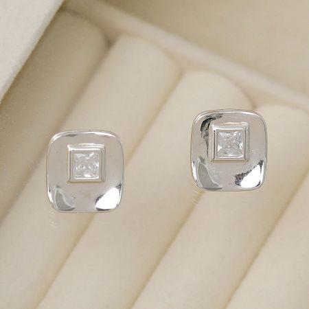 Detailed shot of the silver square stud earrings with brilliant cubic zirconia on a soft velvet surface.
