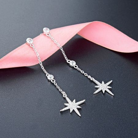 Detailed view of the silver star-shaped earrings with delicate chain details.