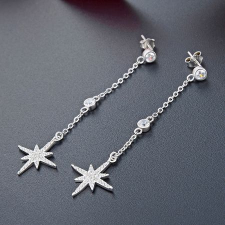 A pair of sterling silver starburst earrings with clear stones embedded in the star and along the chain.