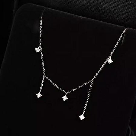The sterling silver necklace with star-shaped zircon charms on a black velvet display stand.