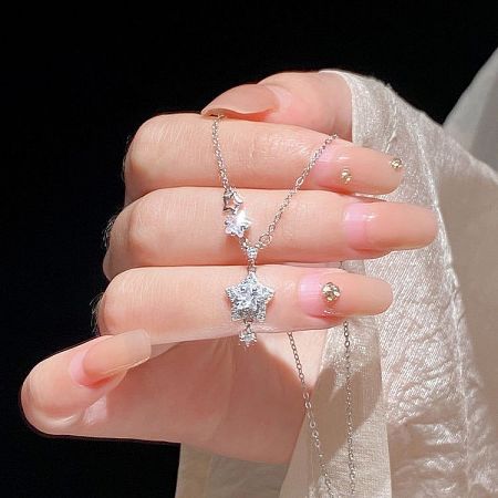 The dainty star necklace held in hand to show its scale and delicate nature.