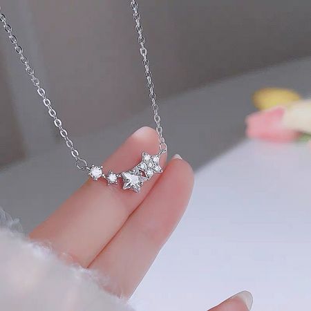 A hand holding the delicate silver star pendant to show its size and craftsmanship.