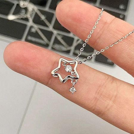 Close-up detail of the zircon-adorned star pendant with a dangling charm.