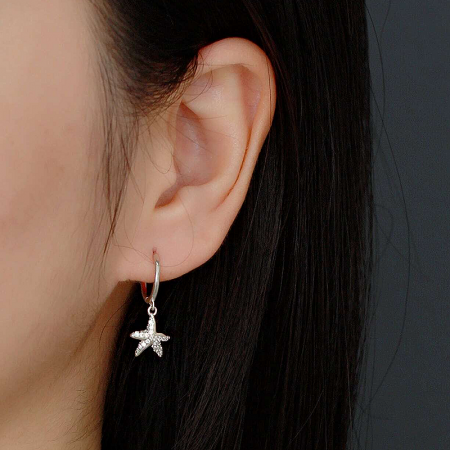 A model wearing the silver 925 sterling silver starfish huggie hoop earring to showcase its size and style.
