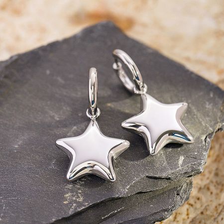 Detailed shot of the silver star-shaped huggie earrings.