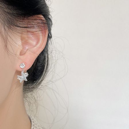 Close-up of the silver starfish earring, showcasing its intricate details and sparkling crystal accent.