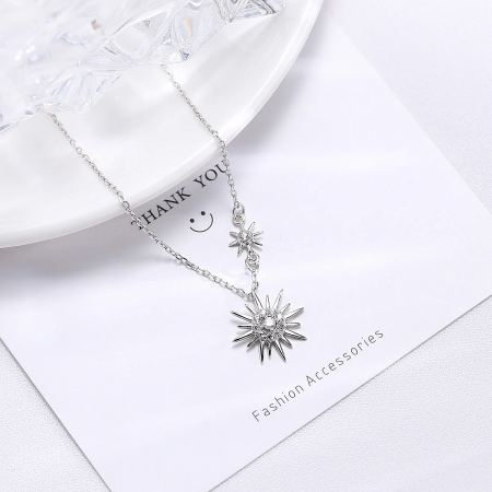 A clear product image of the silver sun-themed necklace against a neutral backdrop.
