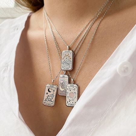 A collection of four silver tarot card necklaces displayed on a white surface.