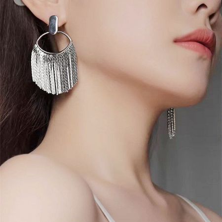A single large silver tassel earring showcasing its intricate design.