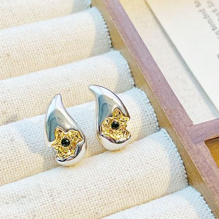 Detailed view of the teardrop-shaped two-tone earrings with a starburst design.