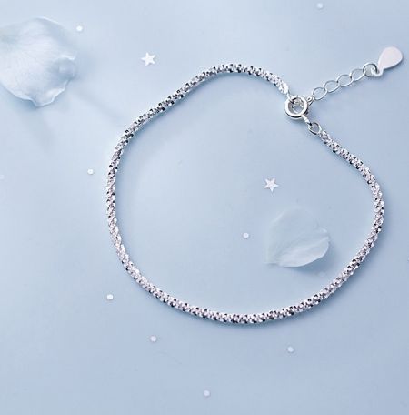 Detailed view of the 925 Sterling Silver Glittering Bracelet's texture on a blue surface.