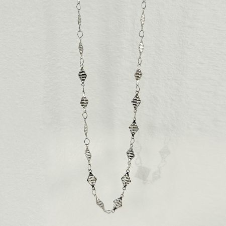 Close-up of the silver waist chain with a unique textured finish on its diamond-shaped elements.