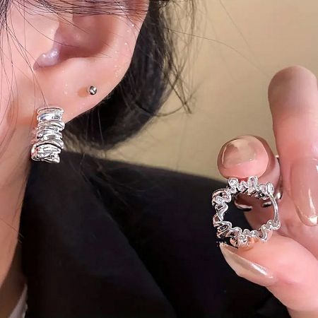 A model showcasing the textured detail of the sterling silver C-shaped hoop earrings.
