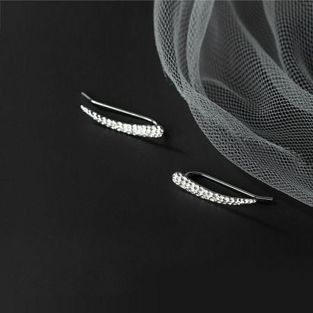 A pair of sterling silver earrings featuring a distinct textured pattern and stone embellishments.