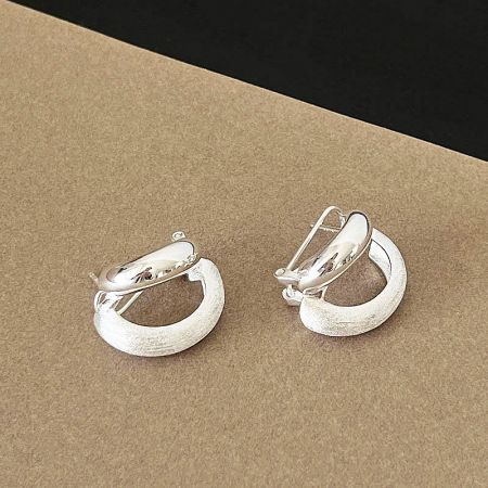 A pair of frosted silver hoop earrings with a hinged back.