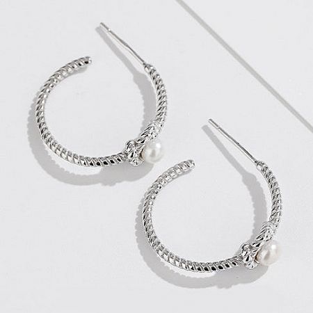 Top-down view of the textured silver and pearl C-shaped stud earrings.