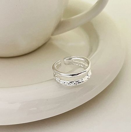 925 Sterling Silver Double Layer Ring - A close-up of the 925 Sterling Silver Double Layer Ring, showcasing its intricate textured band on a white ceramic saucer.