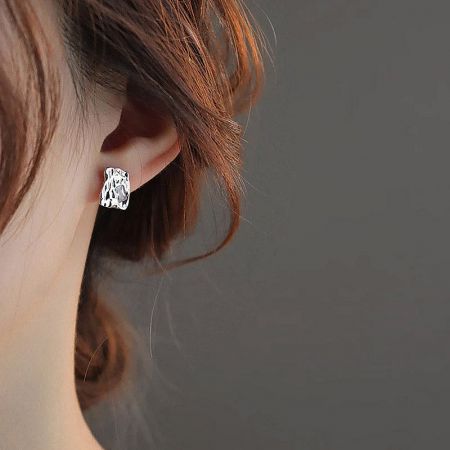 Model wearing a textured square-shaped silver-plated stud earring.