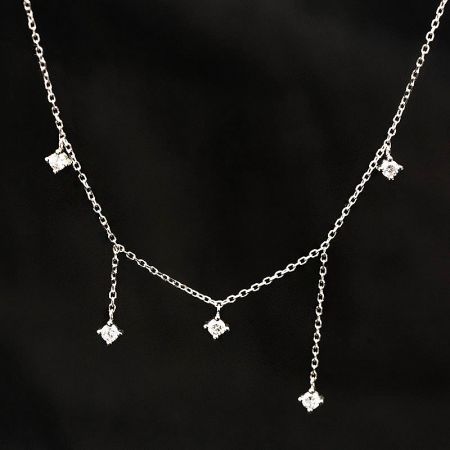 Detailed view of the silver-toned necklace with five diamond-shaped zircon charms.