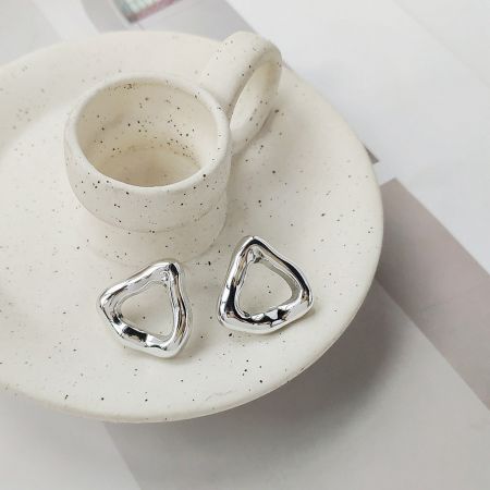 A product shot of the silver-plated geometric triangle hoop earrings showcasing their clean lines and polished finish.