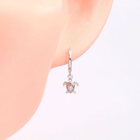 Close-up view of the silver turtle huggie earring being worn.
