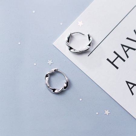 A detailed close-up of the silver twist hoop earrings, emphasizing the intricate rope-like design and polished finish.